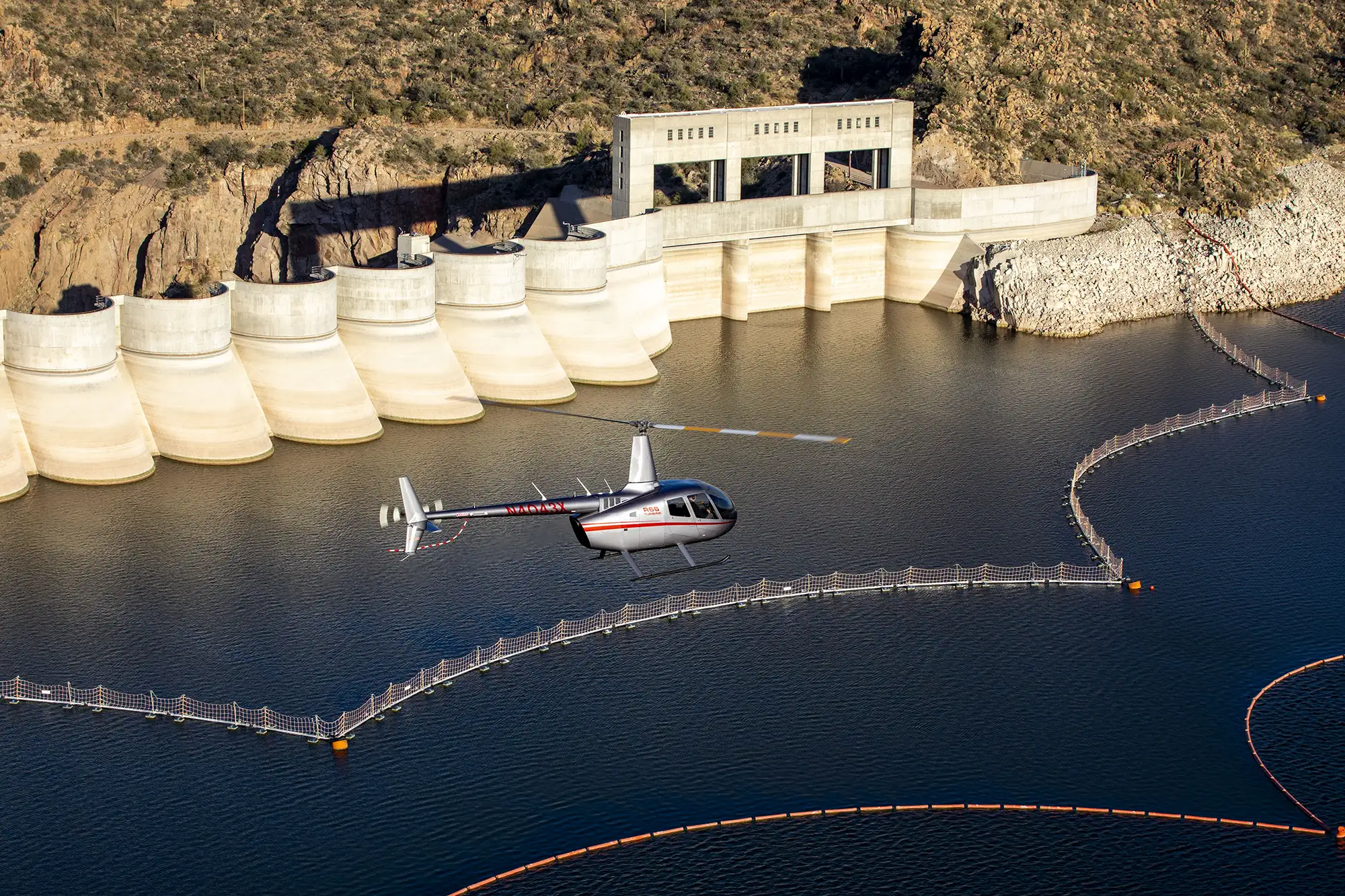 helicopter flying over dam taking aerial photography