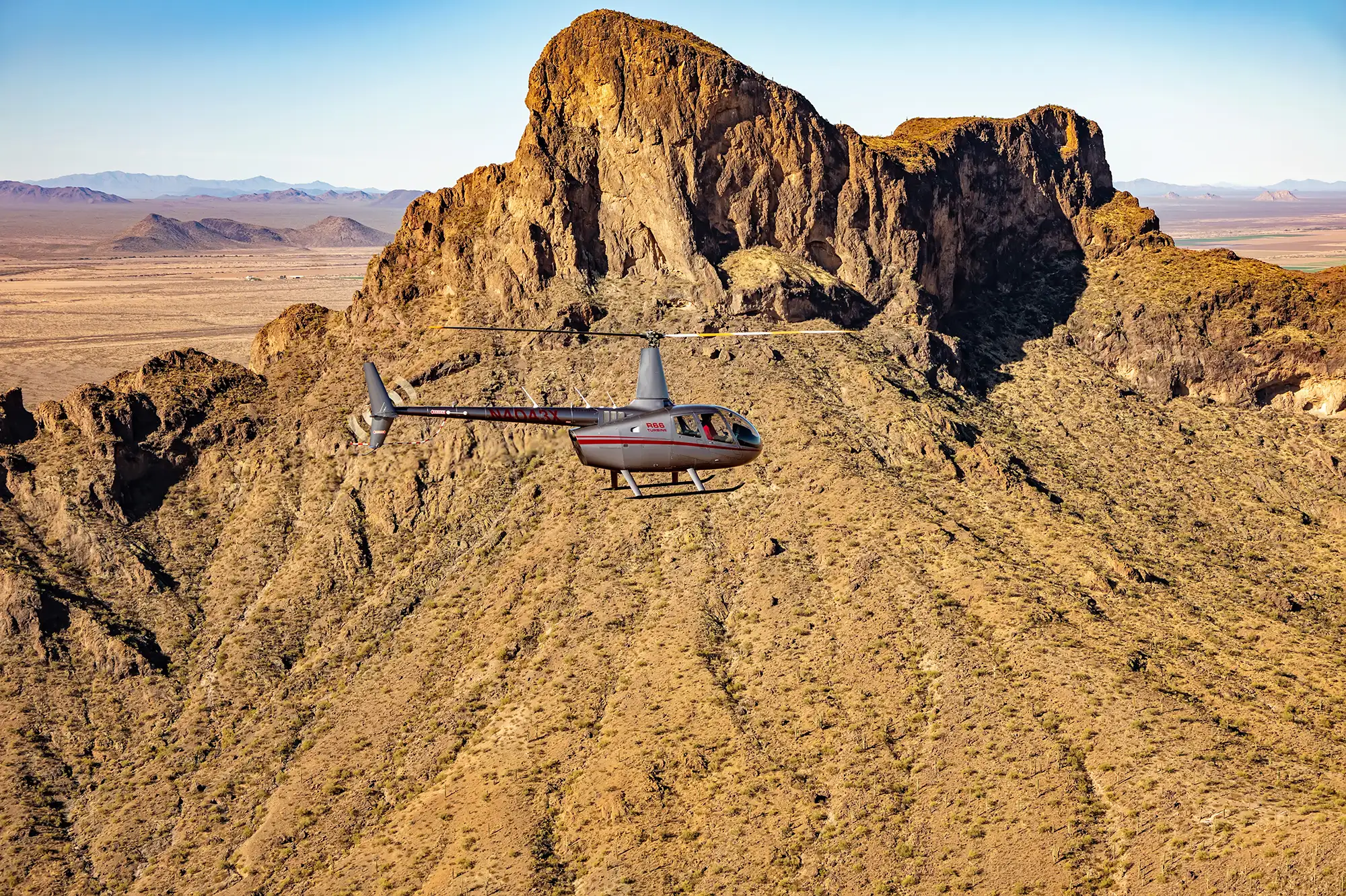 Quantum Helicopters R44 helicopter flying in front of mountain