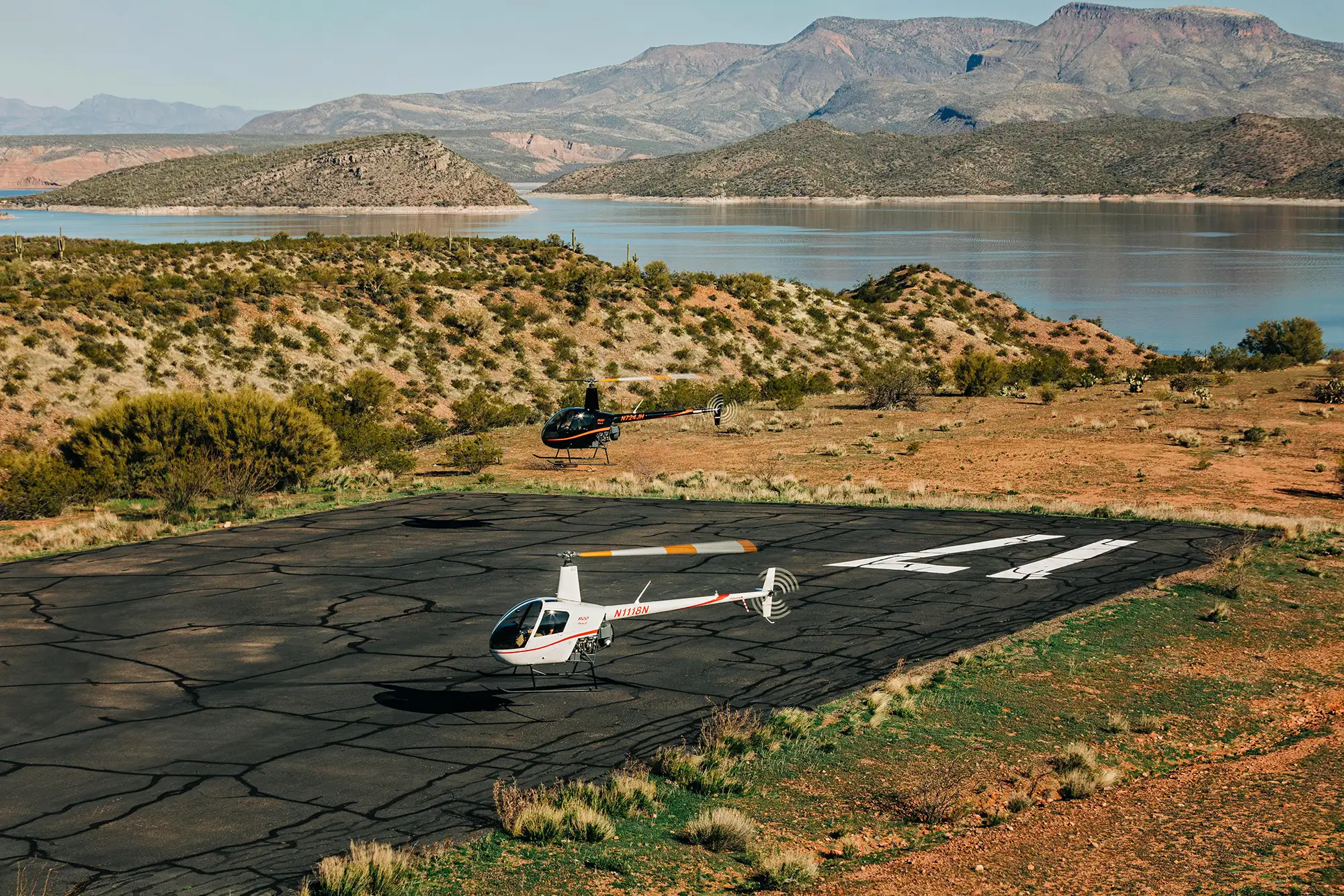 Aerial photography of helicopters taking off at air strip near lake in Arizona